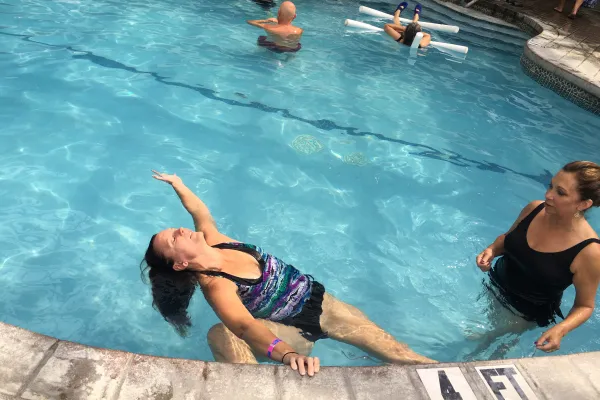 Woman stretching backwards into pool during aqua yoga