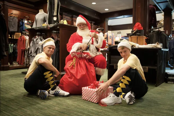 Two men dressed as elves with Santa and his sack of presents in the Crystal Springs Pro Shop 