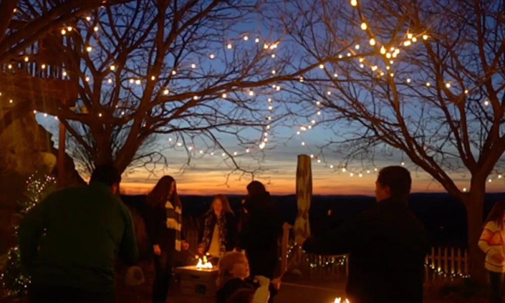 Group of people standing around firepits at nighttime.