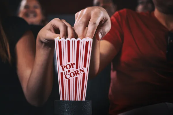 Two hands reaching in to popcorn holder.