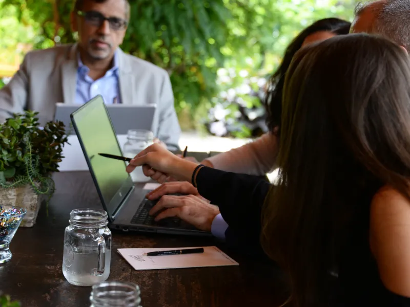 Guests sitting around table looking at laptop.