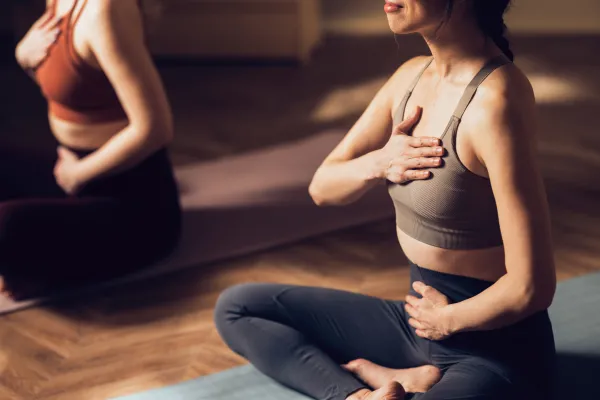 Woman sitting with legs crossed and hands on her chest during yoga. 