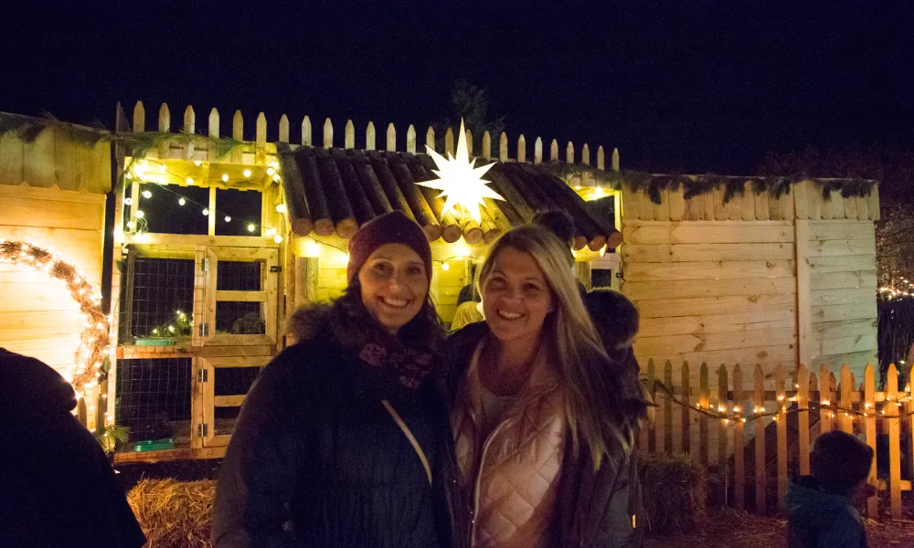 Two women posing for the camera with a Christmas star behind them.