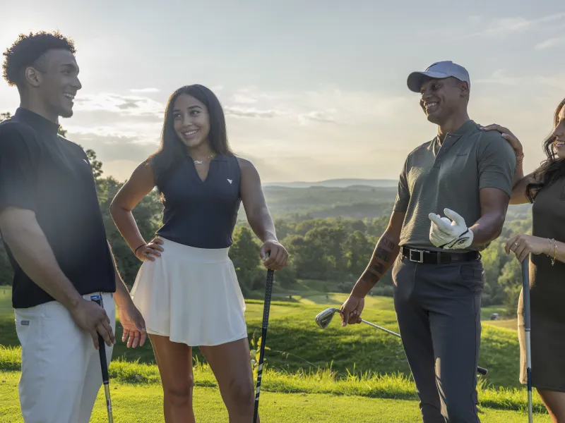 Two women and two men stand together on golf course, 